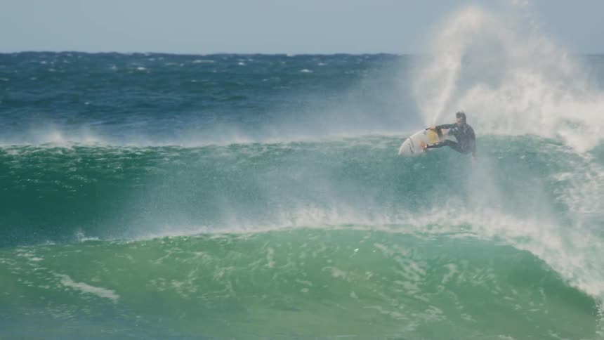 A man rides a surfboard on high strong waves in the ocean