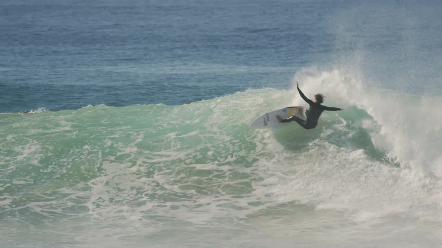 A surfer rides a curling wave on a bright sunny day