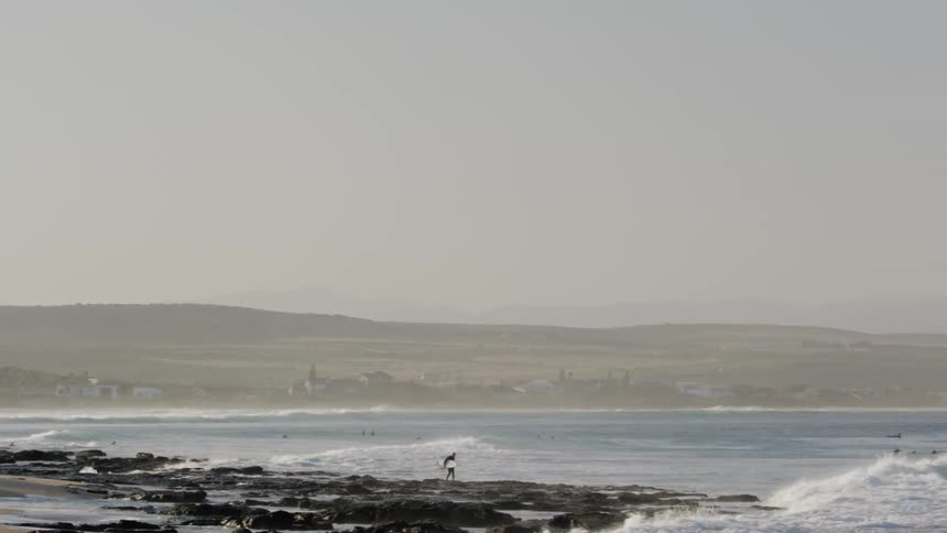 People congregate on a beach as others swim in the water