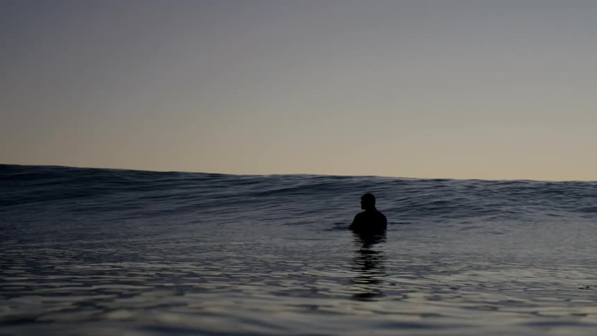 The silhouette of a human shaped figure floating among the ocean waves