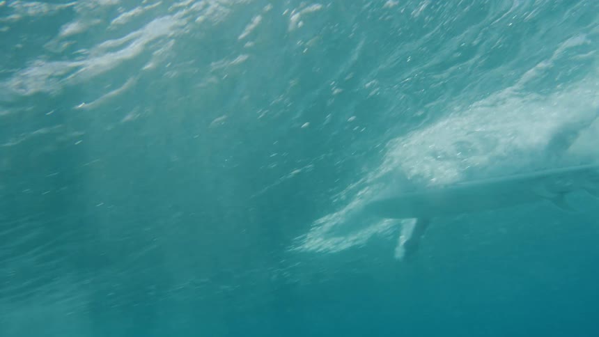 A person on a surfboard paddles out to an ocean wave