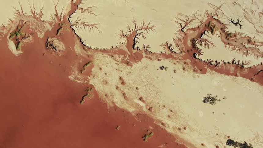 A red colored dried river parting the sands of a desert