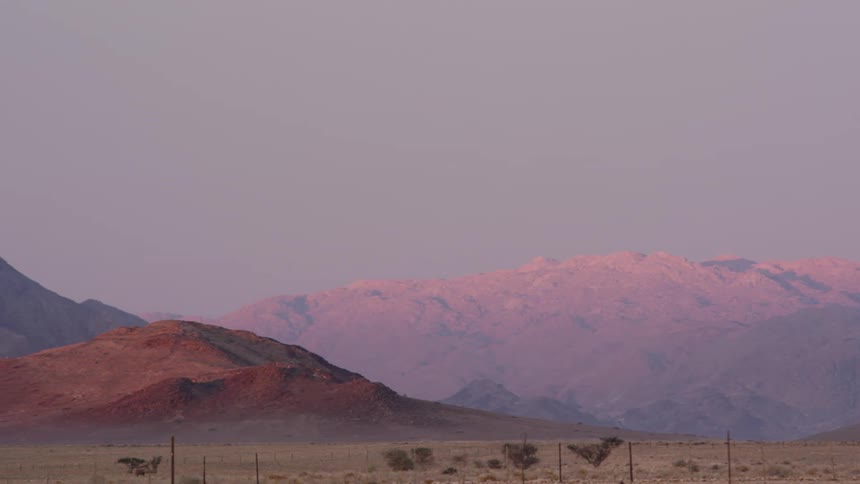 A grassy plain with mountains and the sky in the background