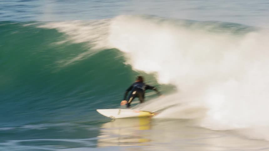 A man with a wet suit surfing in the ocean with a surfboard