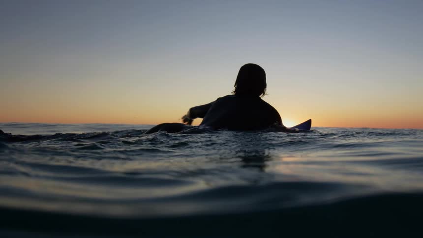 A person laying down on a surfboard in the ocean paddling