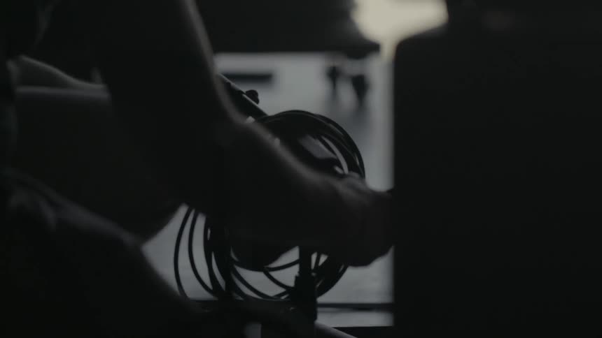 A person adjusting a stand and grabbing a coil of cords