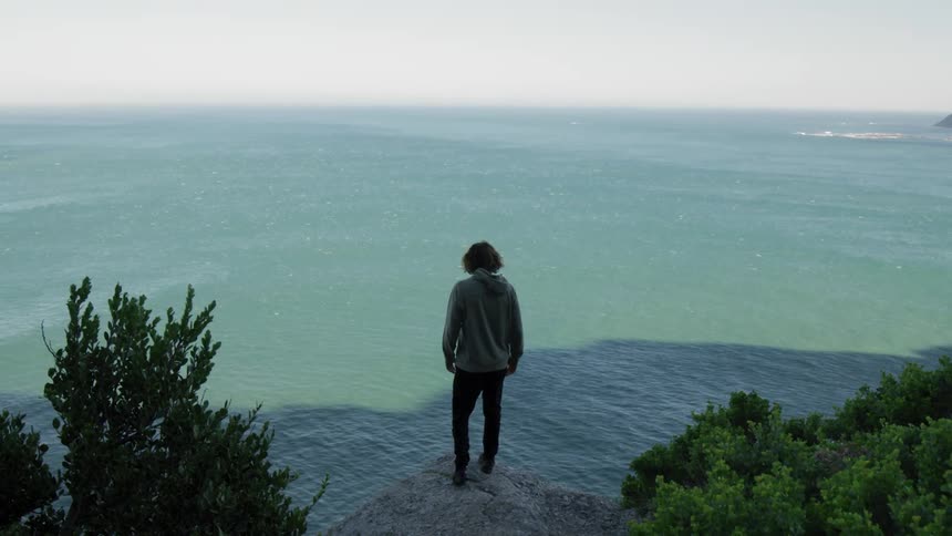 Man walks to the edge of the cliff beside the sea