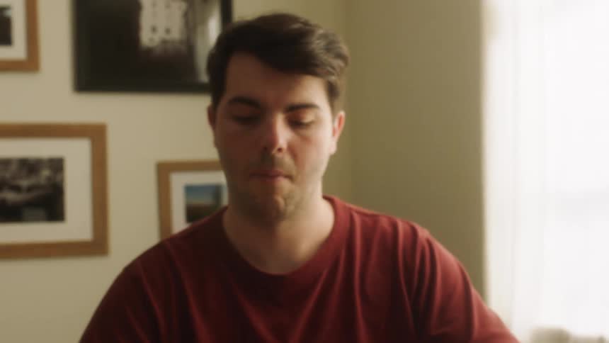 Man sitting at a table in his living room makes a homemade face mask