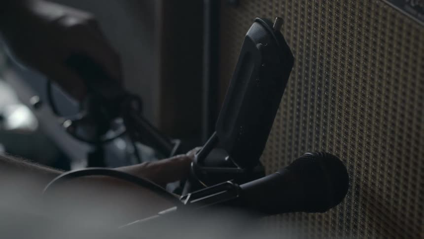 A person adjusting a microphone in front of a speaker