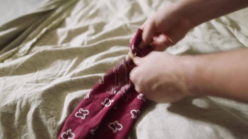 A white person puts a rubber band around a piece of fabric