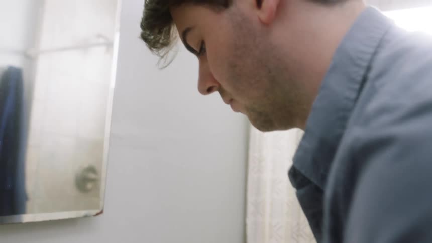 A white man washes his hands at a bathroom sink