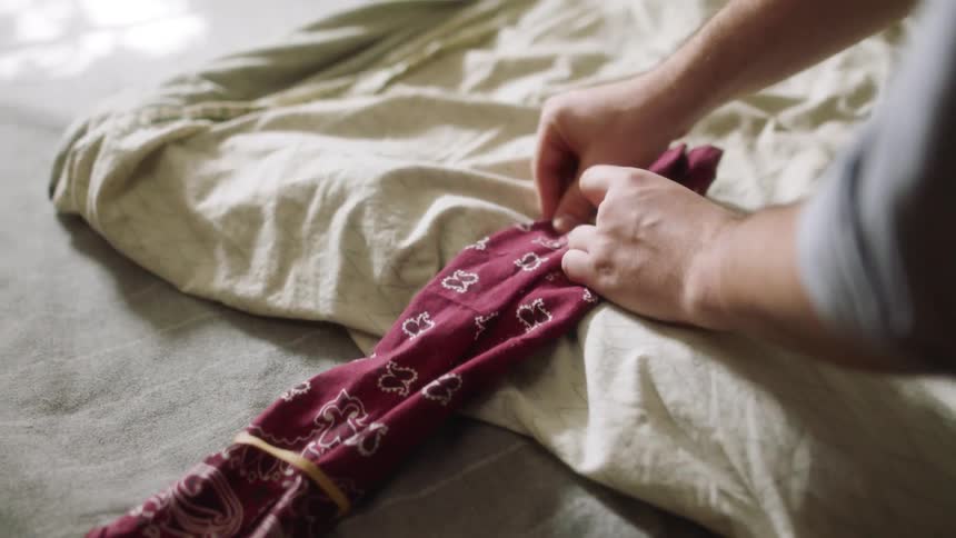 A man puts elastic bands on material and folds it