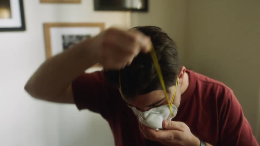 Man sitting at the table wears a face mask and stands up