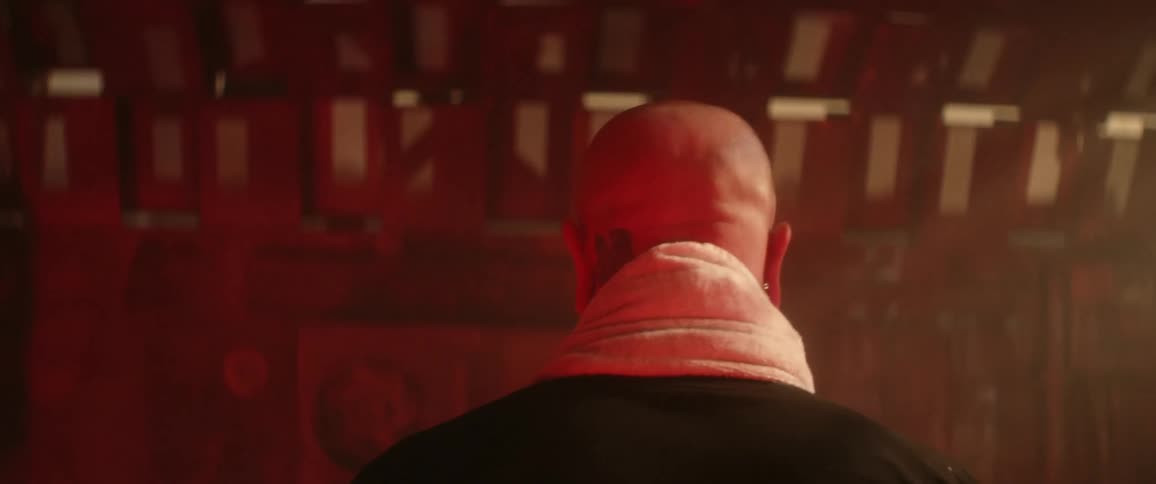 A white man with a towel around his neck walks through a room