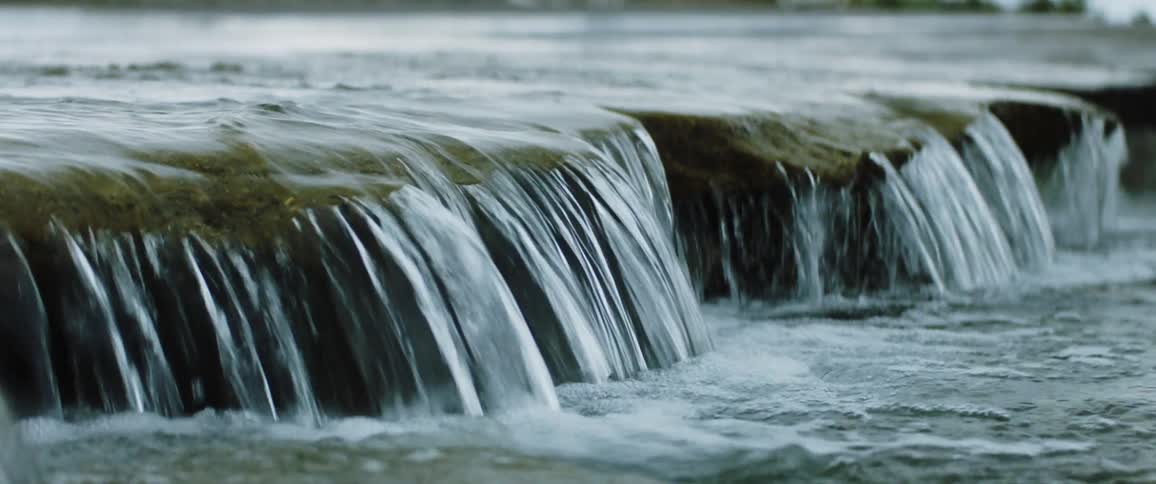 Water flows over the rocks and splashes into the river