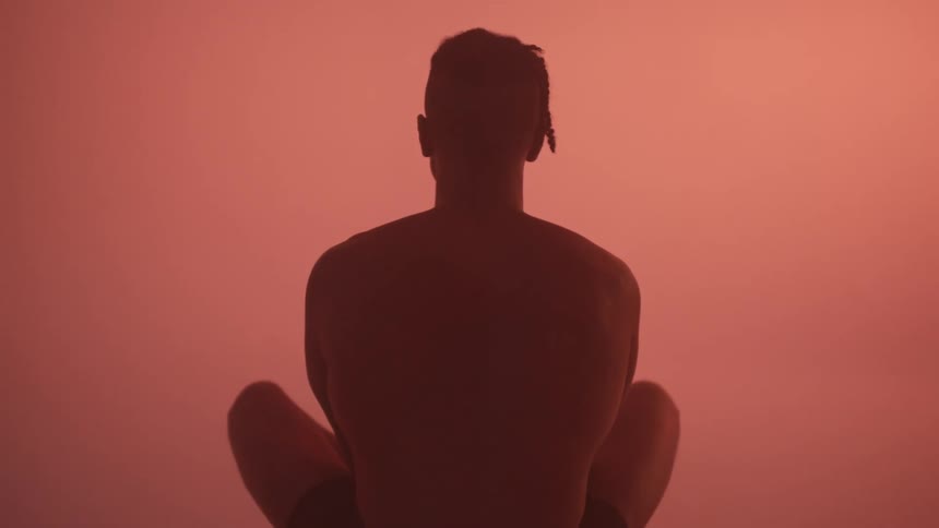 The back of a young man sitting cross legged
