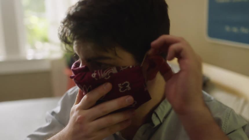 Man sitting on the bed wears a face mask in the bedroom