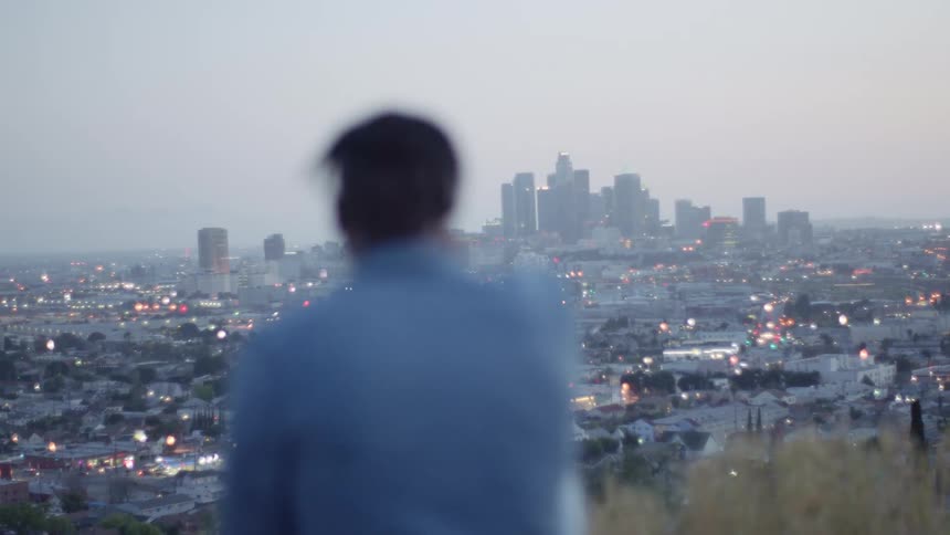 Man sitting on a hill watches the city