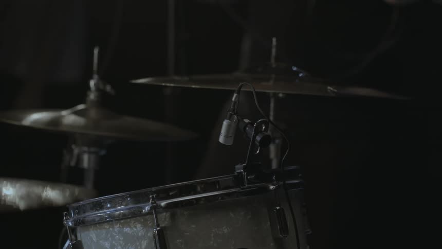 A man is setting up some drums in a dark area