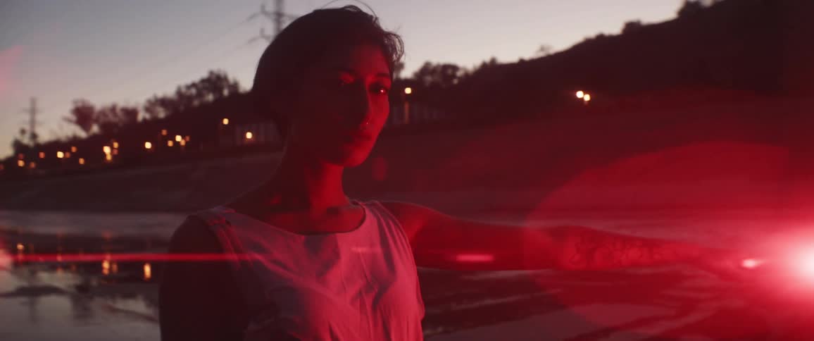 A teenager stands in a road holding a flare