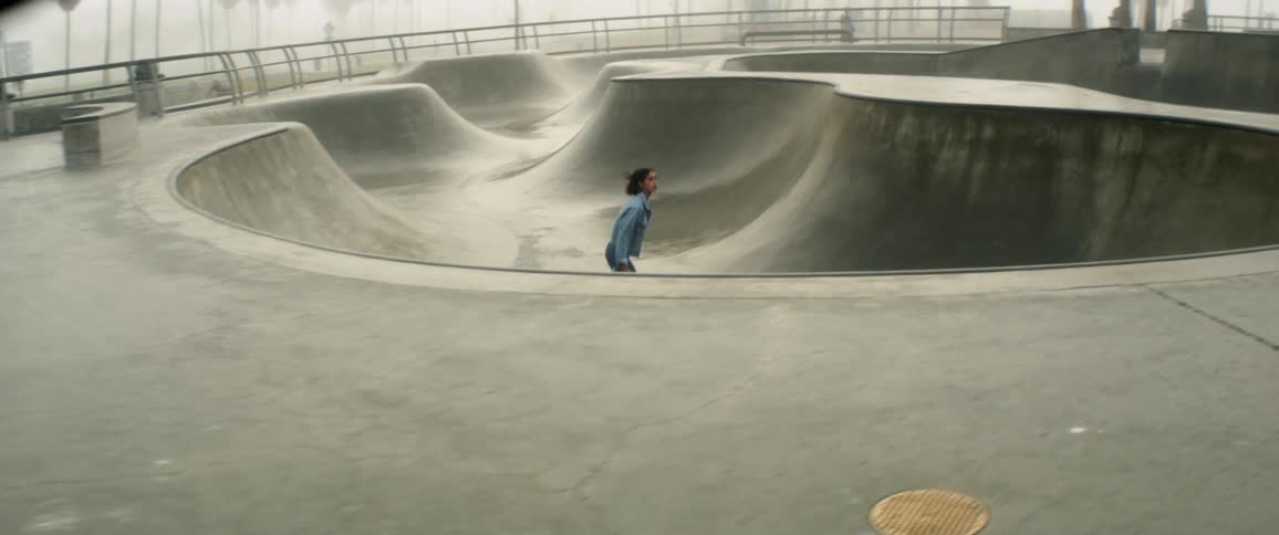 A woman skates at a park and jumps up and over the edge of a concrete pit