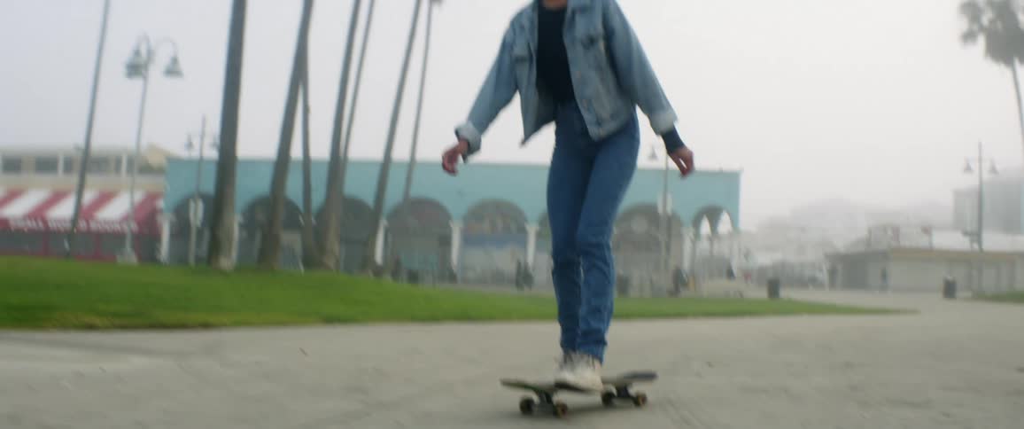Teenage girl skateboards up on a cloudy day