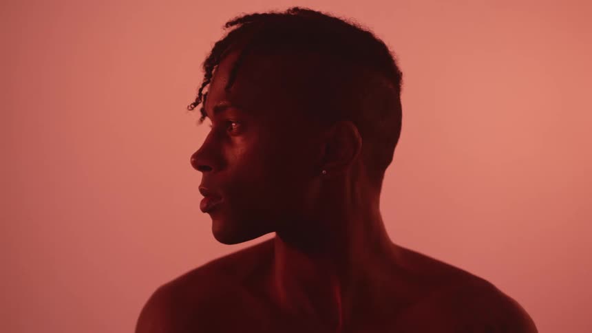 A black man stands with his head facing to the side