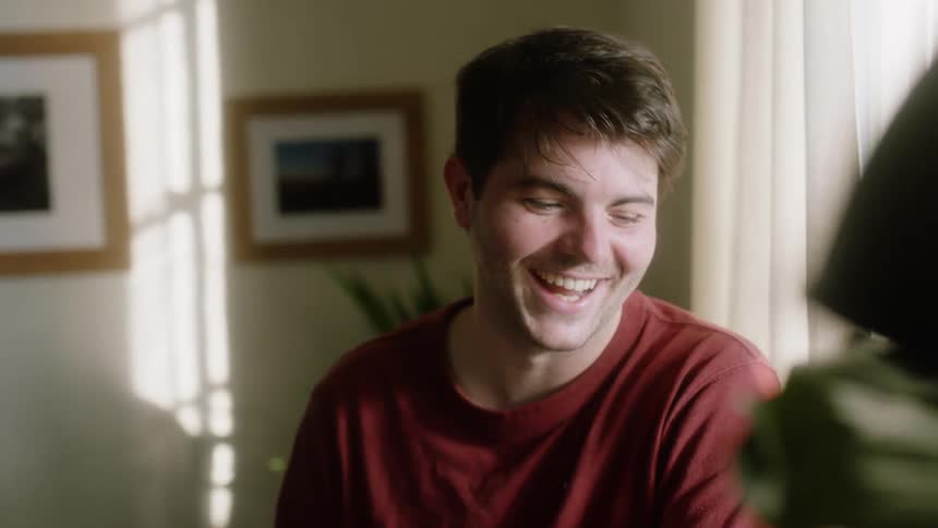 A white man laughs and smiles as he has a conversation