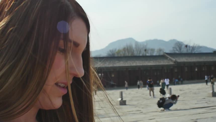 A woman checks her cell phone at an asian tourist destination