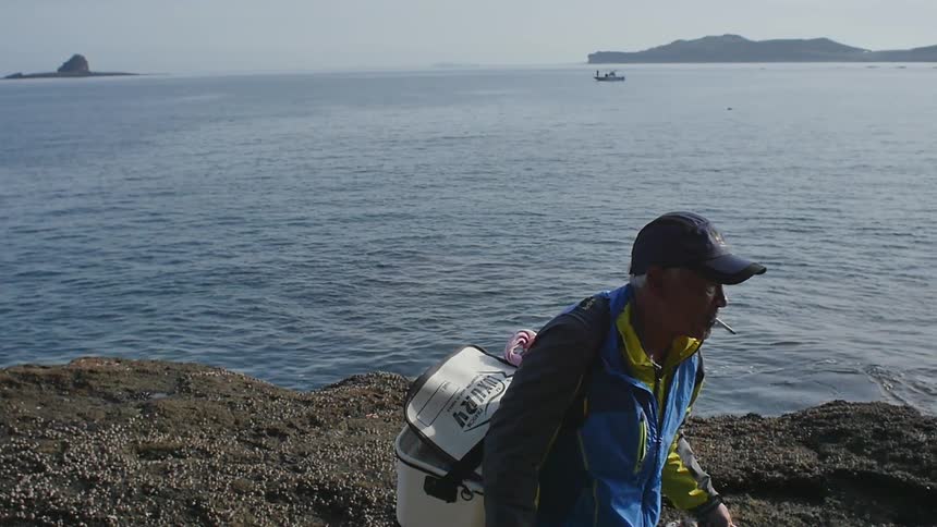 A fisherman walking away from the ocean