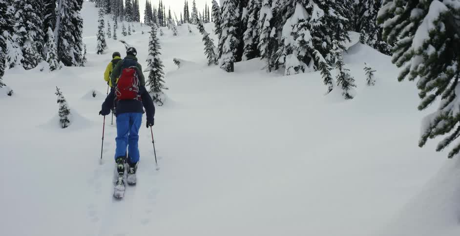 Three people on skis hiking up a mountain