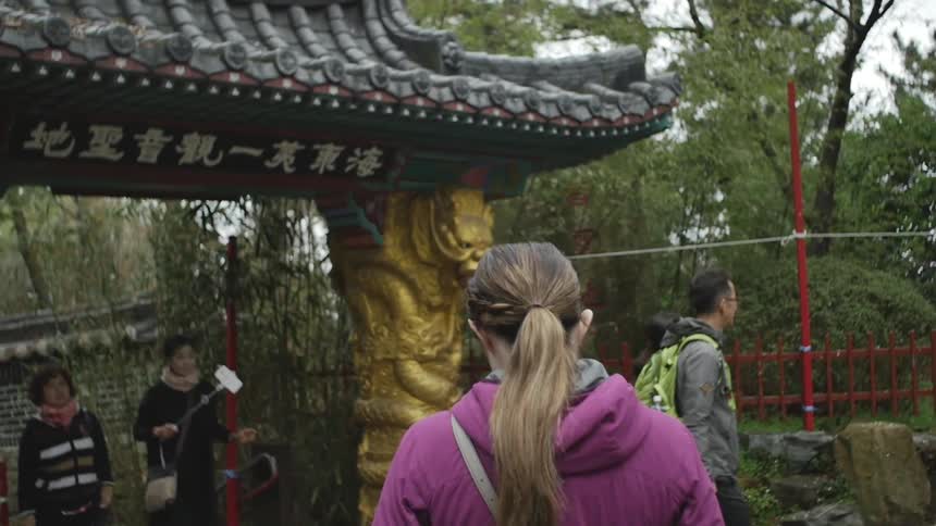 A woman in a purple jacket walks toward a gate