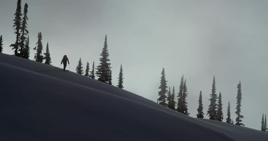 A skier moves across a snow slope on a mountain