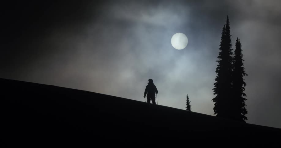 The moon shines over a skier at night