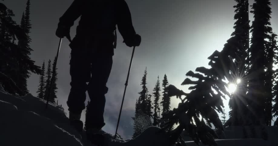 The person walks through the snow in silhouette