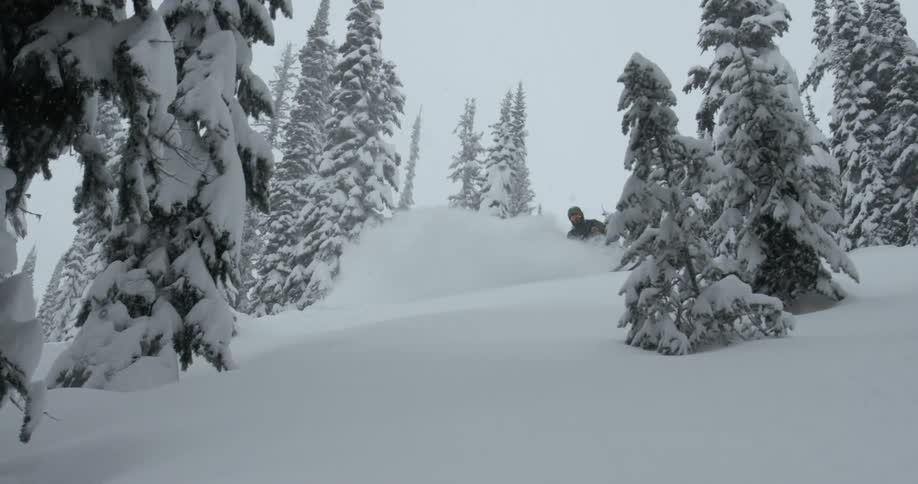 A person skis down a hill as snow falls