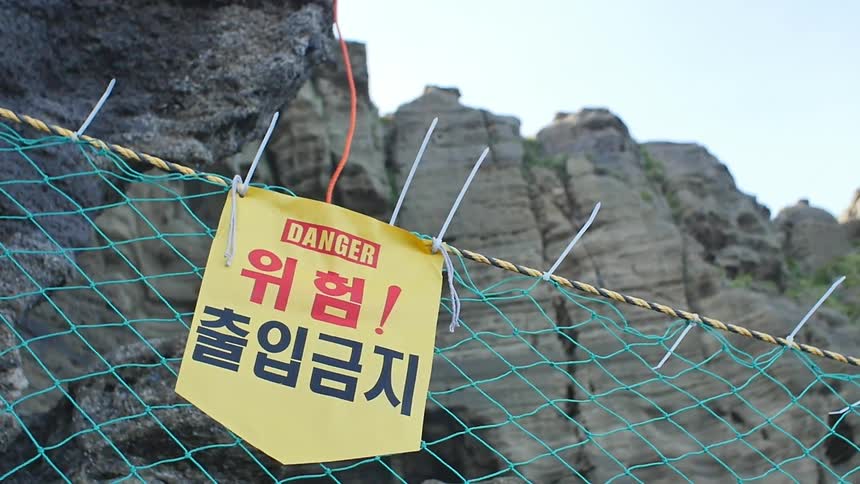 A fence has a yellow danger sign on it