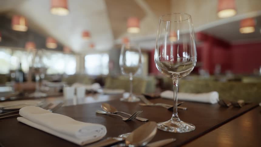A restaurant table is set with glasses and utensils