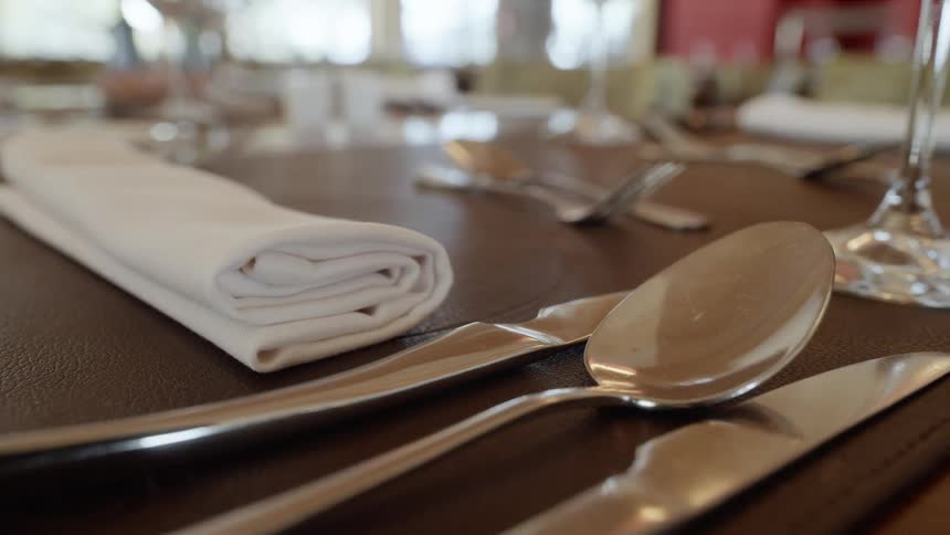 Tables are set with silverware and glasses in a restaurant