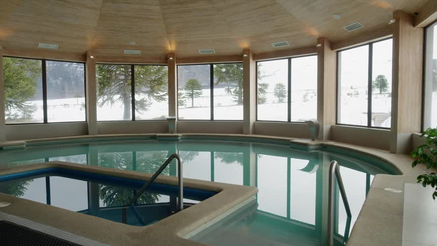 A large luxurious public bath with windows showing a snowy landscape outdoors