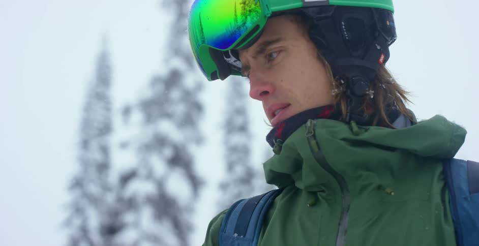 A man stands in the falling snow and looks ahead