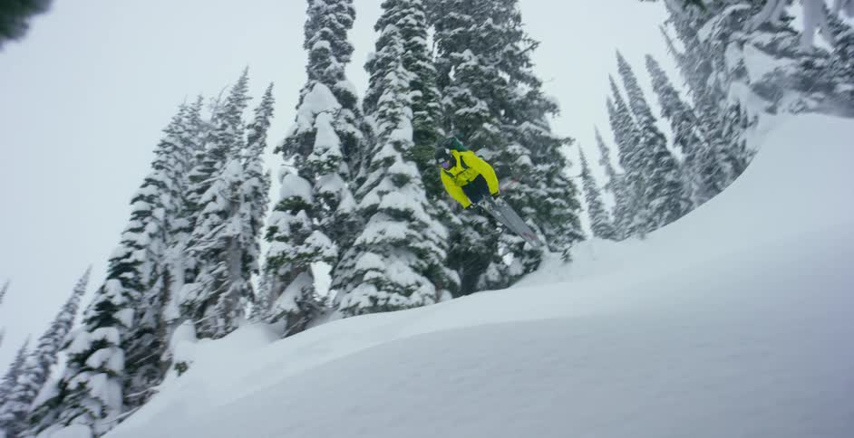 A skier does a trick off a jump in a snowy forest