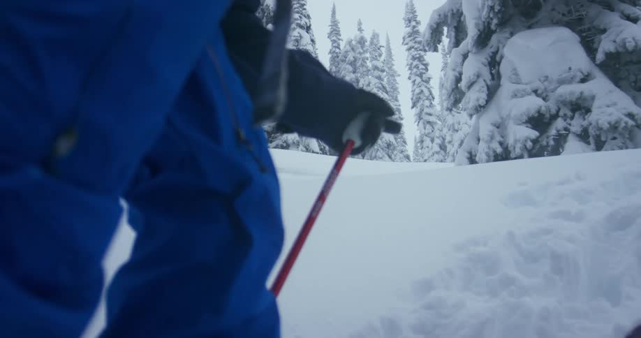 Two people hike on skis up a steep snow covered hill