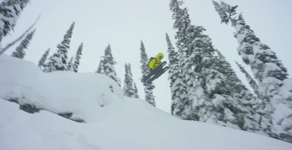 A skier flying over a ledge and landing on a slope