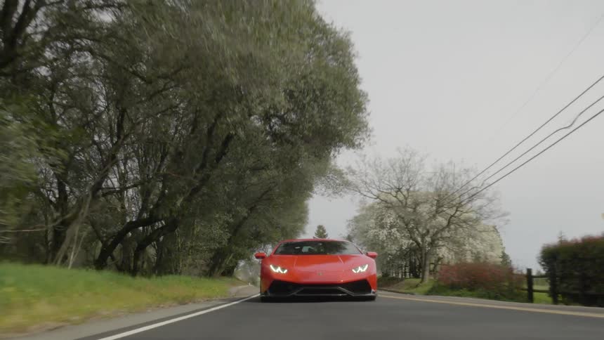 A sports car drives on a rural road