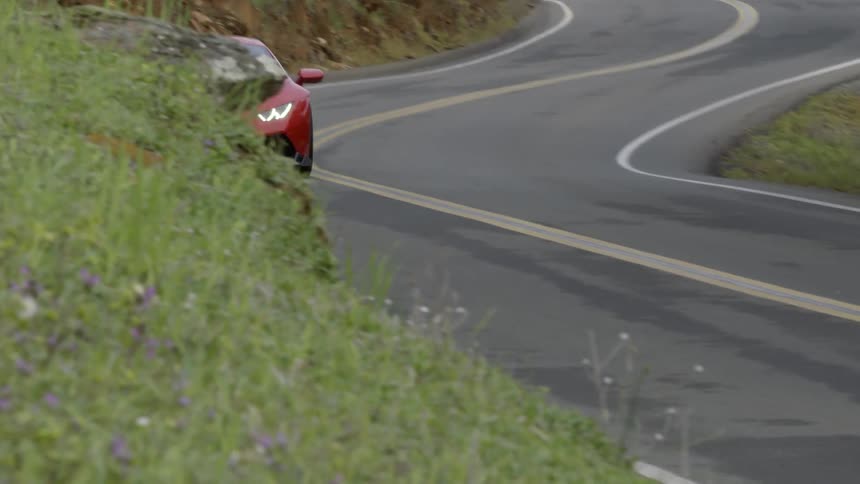 A red car races down a curved highway