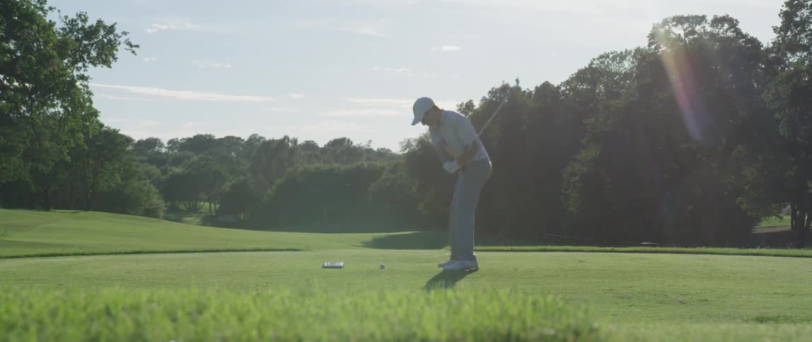 A golfer hits a ball on a golf course
