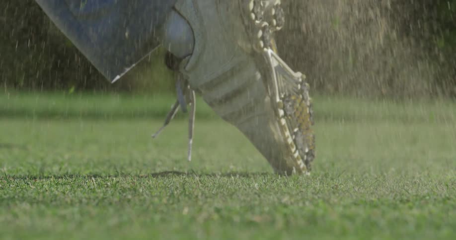 A club striking a golf ball and the golfer's foot turning during the swing