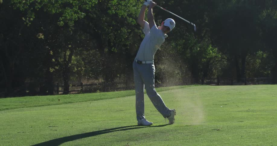 A teenage boy swinging a golf club