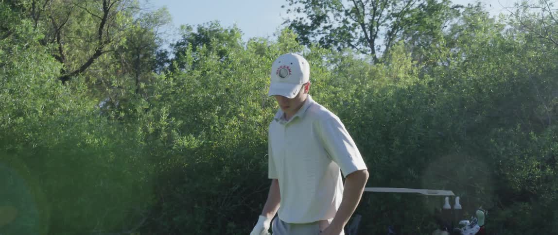 Golfer walking to his place and putting his ball on a tee
